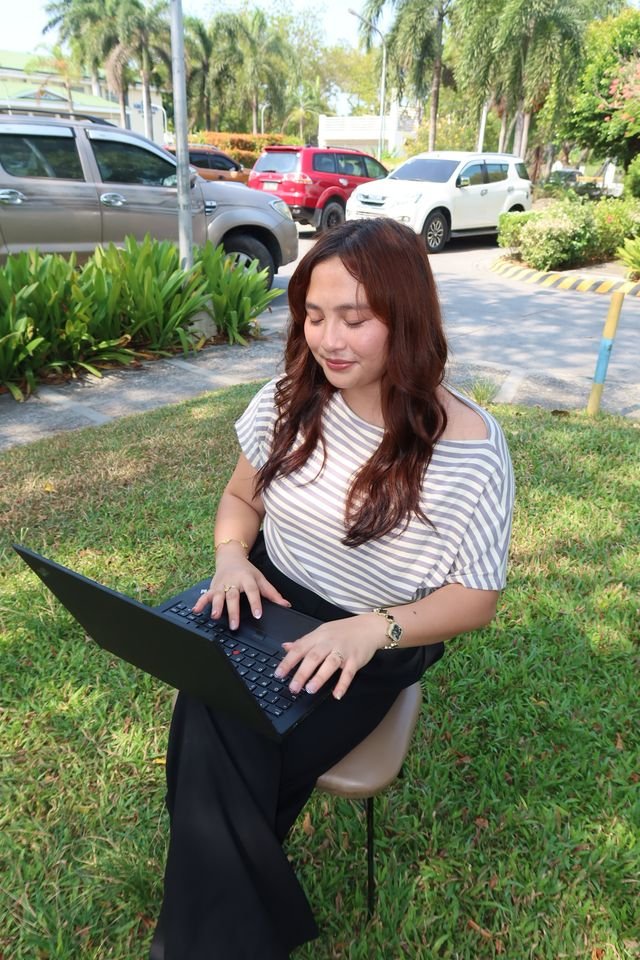 A team member working on a laptop on the grass